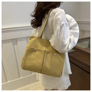 Detail of ginger yellow canvas tote bag featuring double front pockets and silver snap buttons