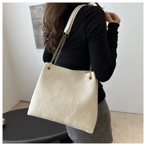 Détail du sac cabas beige en cuir PU texturé avec bandoulière à chaîne dorée élégante