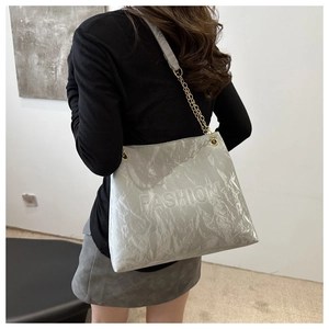 Détail du sac cabas plissé argenté avec chaîne dorée et logo gaufré tendance