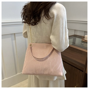 Detail of light pink tote bag featuring crinkled texture fabric and embossed fashion text