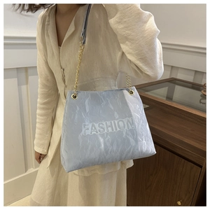 Détail du sac cabas bleu clair avec texte FASHION gaufré et anses en chaîne dorée