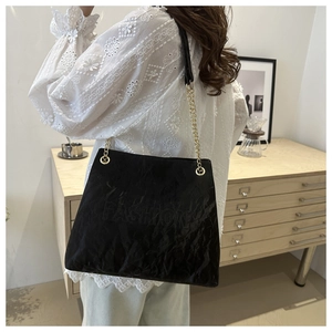 Detail of black pleated tote bag with FASHION embossed logo and gold chain strap