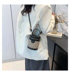 Detail of vintage bucket bag with monogram pattern and leather strap on model