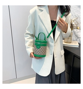 On-body view of a mini green bucket bag with monogram pattern and leather handle