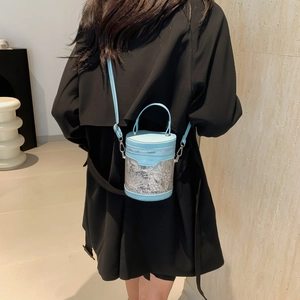 Light blue bucket bag with white embroidery shown in a back-view model carry