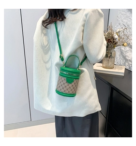 Mini green leather bucket bag with monogram pattern shown on a model in a modern room