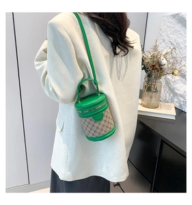 Chic green and beige cylindrical bucket bag with leather accents on a female model