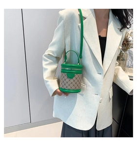 Detail view of mini green leather and canvas bucket bag worn with a white blazer