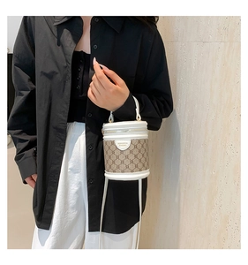 Brown monogram bucket bag with white leather trim worn by model against a neutral wall