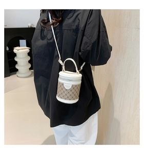 Close-up of retro cylinder bucket bag with monogram pattern and white leather straps