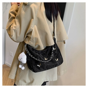 Detail of black hobo bag with silver butterfly charms and white plush cloud pendant