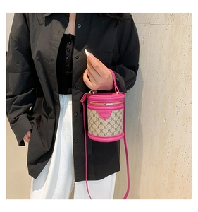 Detail of rose pink bucket bag with vintage monogram and leather handle on shoulder