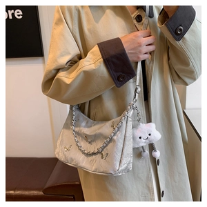 Detail of light gray pleated shoulder bag with silver butterfly charm and chain strap
