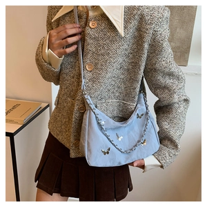 Gros plan d'un sac sous le bras en satin bleu clair avec papillons argentés et chaîne