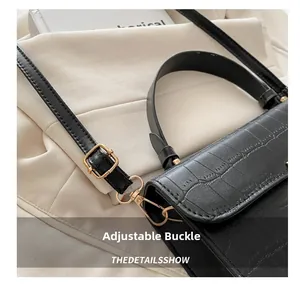 Dettaglio della borsa in pelle nera goffrata coccodrillo con fibbie dorate regolabili