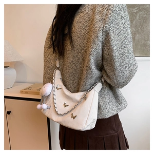 White crescent crossbody bag with silver butterfly charms shown on model back