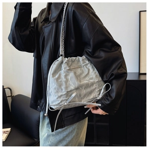 Nahaufnahme der silbergrauen Kordelzug-Beuteltasche mit Metallkette und Schleifendetail