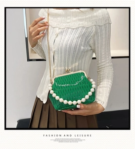 Detailed view of green woven frame bag with oversized pearl handle and gold chain strap