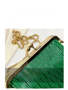 Detail of green clutch bag with vertical ripple texture and gold spherical clasp hardware