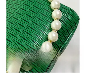 Close-up of white pearl bracelet featuring golden rhinestone spacers on green background