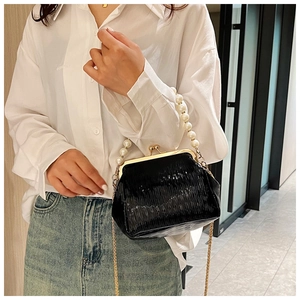Detail of black vintage kiss-lock bag with large pearl handle and golden chain strap