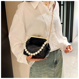 Detail of black pleated evening clutch bag with pearl handle and gold chain strap