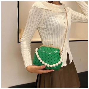 Macro shot of vibrant green pleated shell bag with large pearl strap and gold chain detail