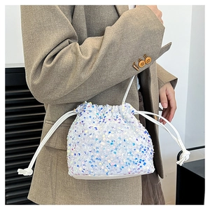 Détail d'un sac seau blanc à paillettes irisées porté sur un blazer pour femme chic