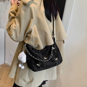 Black Y2K underarm bag with silver butterfly charms and chain on model's shoulder