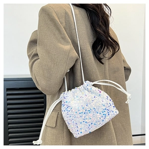 Détail du sac seau scintillant avec paillettes et cordon blanc porté par un mannequin