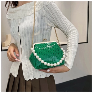 Detail of green pleated crossbody bag with pearl handle and golden chain strap