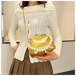 Detail of gold pleated shell bag with pearl handle and metal chain for evening wear
