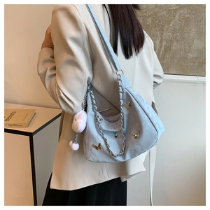 Détail du sac bandoulière bleu clair avec papillons dorés et pompon blanc duveteux