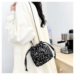 Vue latérale d'un sac seau noir à paillettes avec cordon porté par un mannequin