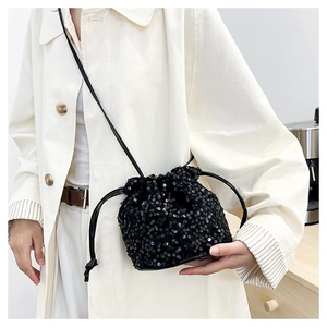 Détail d'un sac seau chic à paillettes noires avec cordon de serrage et bandoulière fine