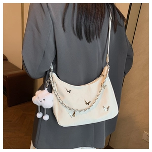 Détail du sac demi-lune crème avec décoration papillon argenté et breloque nuage