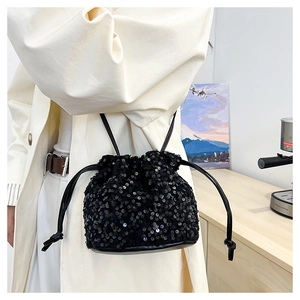 Détail d'un sac seau noir à paillettes avec cordon de serrage porté par un mannequin