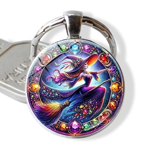 Detailed view of witch riding broom on a glass cabochon keychain with alloy border