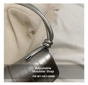 Detail of silver metallic shoulder bag with adjustable thick rope strap and textured finish
