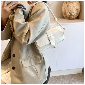 Detail of cream crocodile embossed leather shoulder bag with stylish knot handle and flap