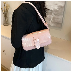 Close-up of pink glossy crocodile pattern faux leather shoulder bag on a model