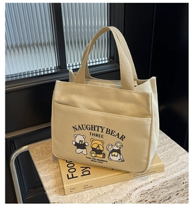 Detail of off-white canvas tote bag featuring naughty bear prints on a prop book