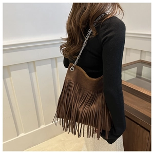 Detail of dark brown suede shoulder bag with long fringes and silver chain strap