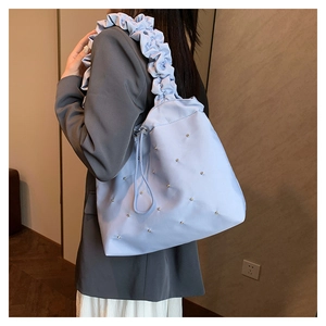 Detail of light blue pleated shoulder bag with delicate pearl accents and drawstring closure