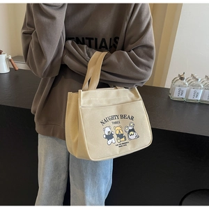 Detail of a beige canvas tote bag with cartoon bear prints held by a model