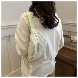 Detailed back view of a light green quilted fabric crossbody chest bag on a model
