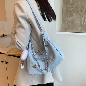 Sac bandoulière bleu clair texturé avec papillons dorés et pompon blanc en peluche