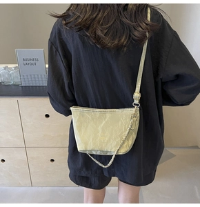Vue détaillée d'un sac seau plissé vert clair avec une bandoulière réglable et dorée