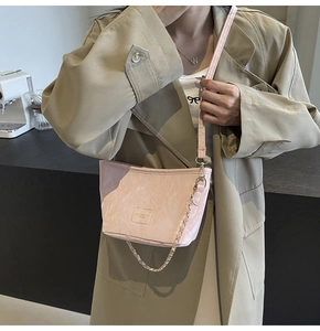 Détail du sac seau rose avec texture plissée et bandoulière en chaîne dorée