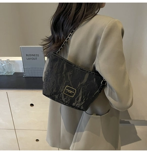 Mannequin portant un sac seau noir froncé avec chaîne dorée et plaque métallique